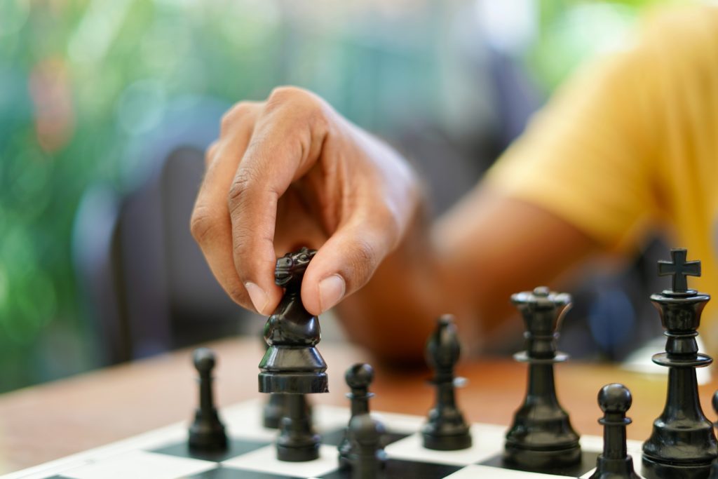 Main déplaçant une pièce d'échecs sur un échiquier.