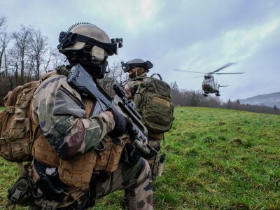Soldats en tenue de camouflage avec hélicoptère en arrière-plan.
